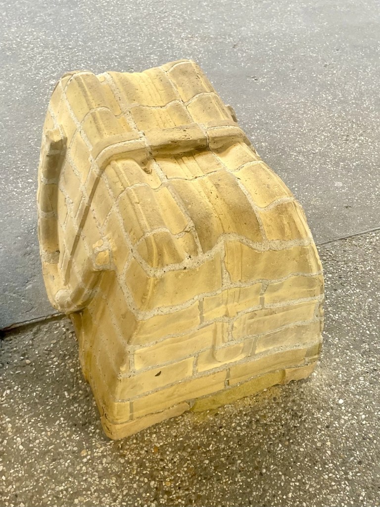 En gul murstein-lignende struktur som ligner på en kasse, plassert på en grå overflate.